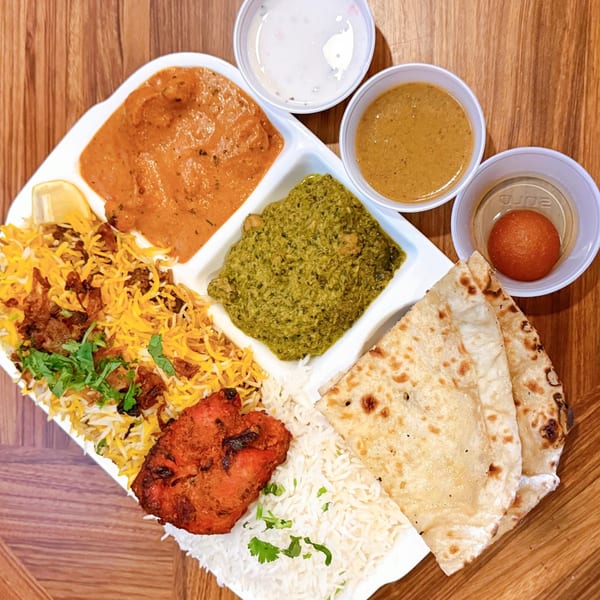 A House of Biryanis and Kebabs platter with biryani, chicken tikka, curries, naan, and gulab jamun.